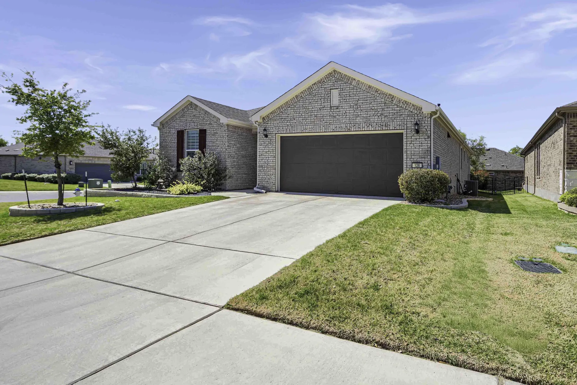 Front exterior from street — driveway, landscaping and mature trees