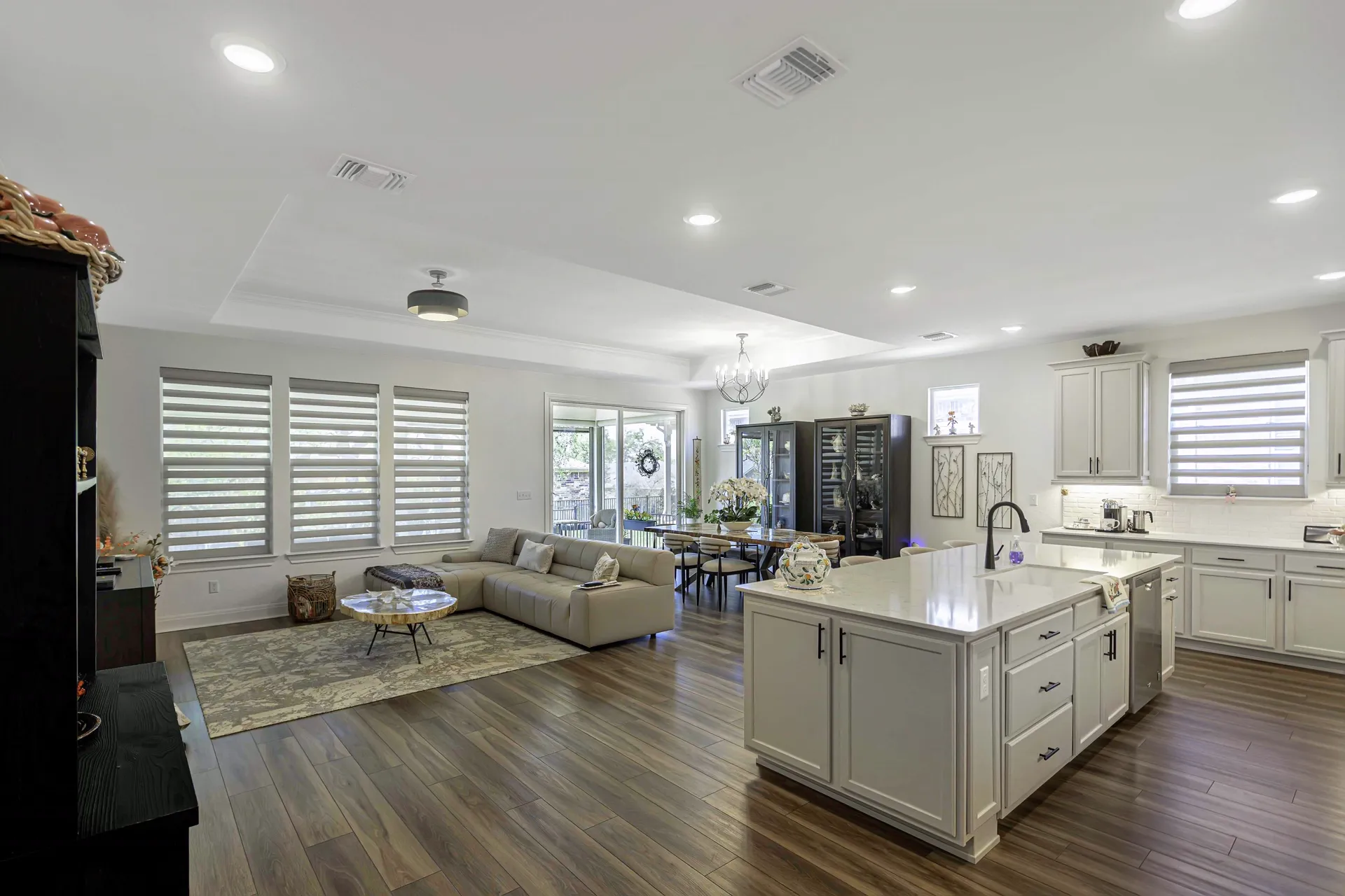 Open-concept living and kitchen with plantation shutters and area rug