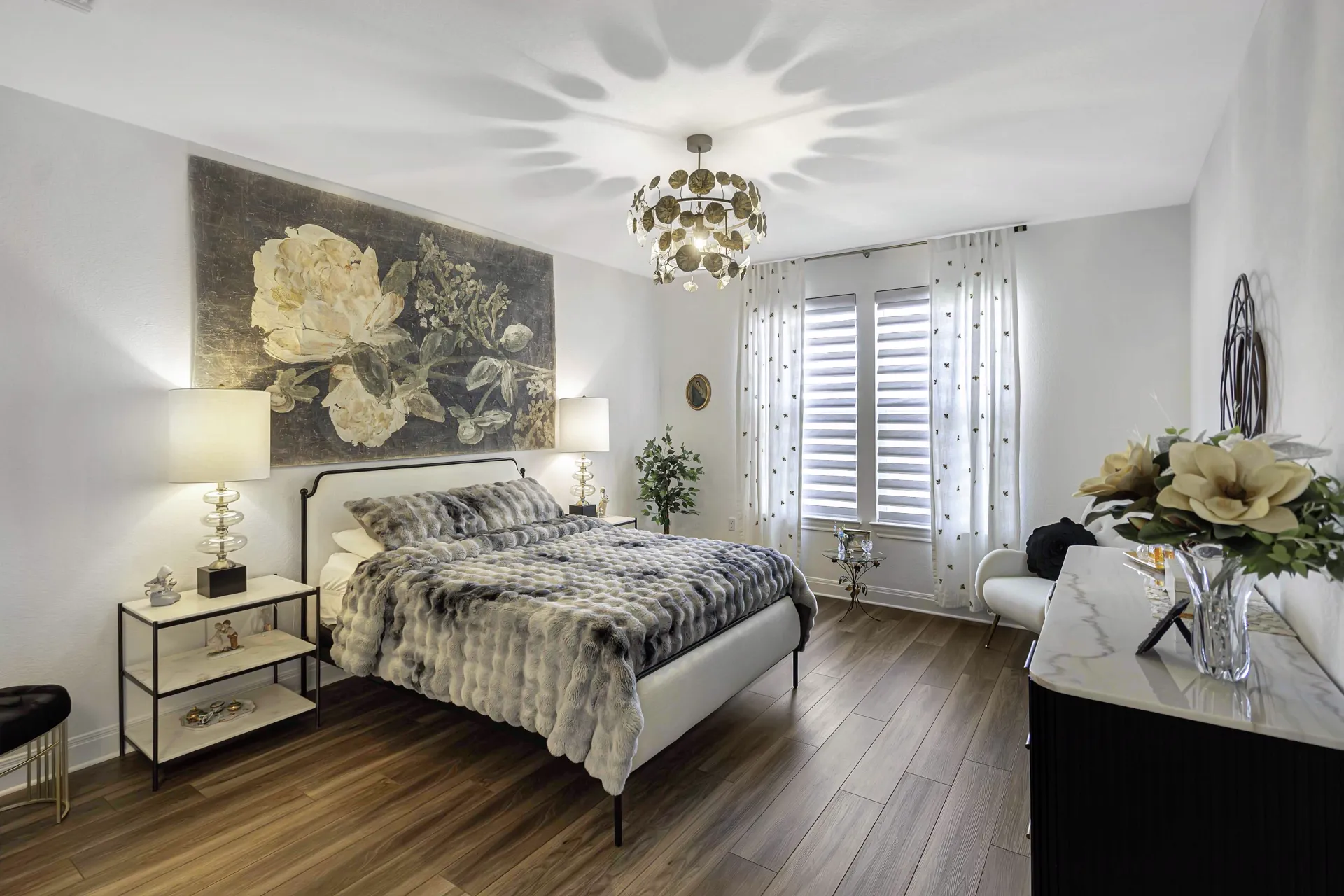 Primary bedroom with floral accent wall, chandelier and elegant decor